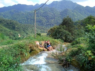 Travelers resting quietly near Hieu Waterfall during a private walking journey in Pu Luong