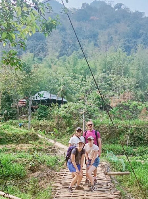 Local trekking guide walking with travelers through village paths in Pu Luong