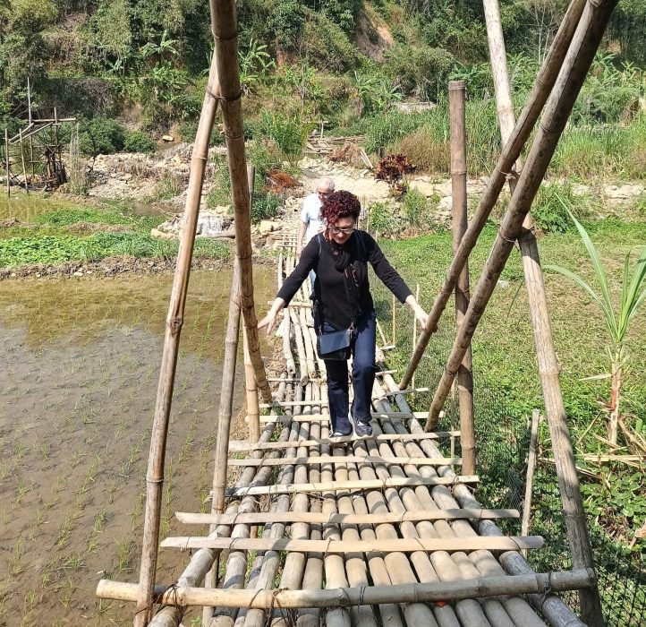Crossing a traditional bamboo bridge on a 3-day Pu Luong trekking itinerary, where trails connect villages through rice fields and forest paths.