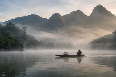 Wooden boat on Ba Be Lake surrounded by misty mountains