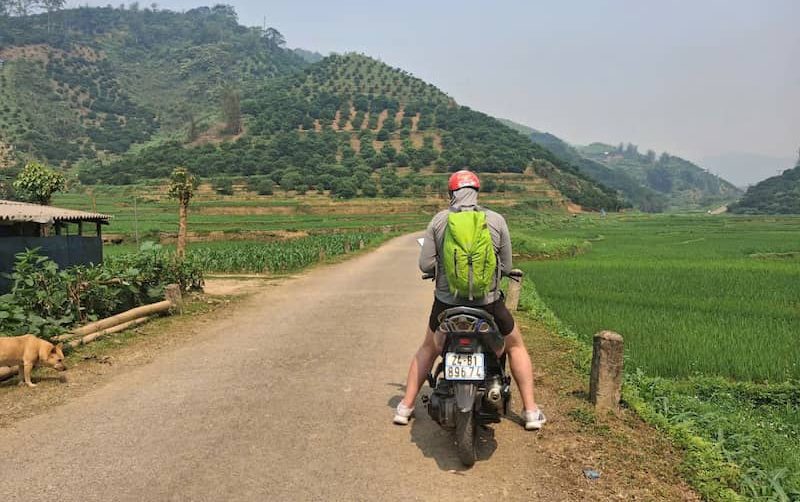 Traveler riding a motorbike through scenic mountain roads in Pu Luong Vietnam
