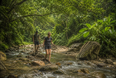 Travelers crossing small river during jungle trekking in Vietnam