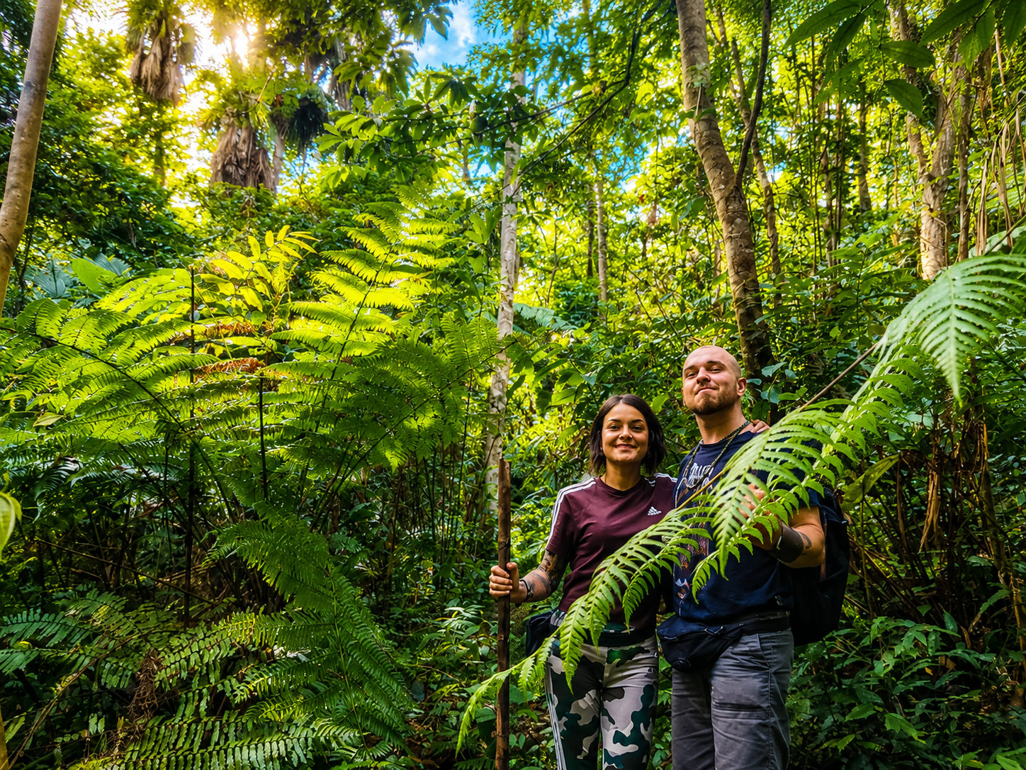 International travelers trekking with walking sticks through a dense forest trail during the second day of a private Pu Luong journey